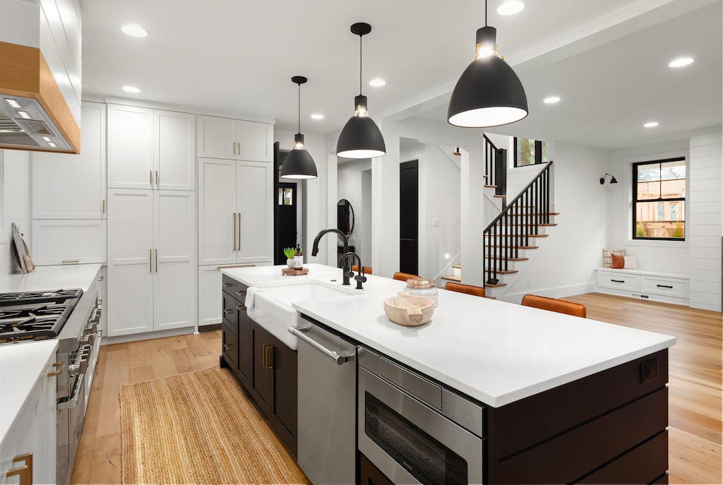 Modern lighting in updated kitchen. Black matte pendants, white cabinets and white countertops. 