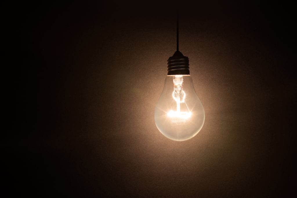 Brightly lit lightbulb against a black background.
