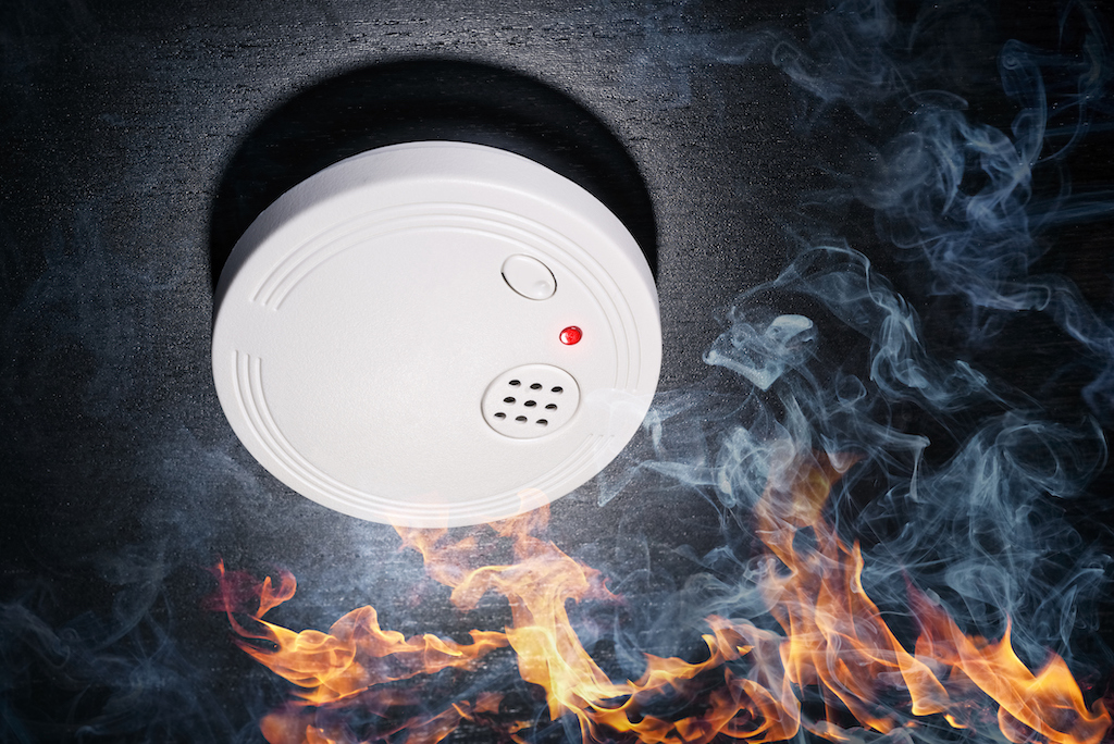 Smoke detector alarm going off from smoke and fire in home.