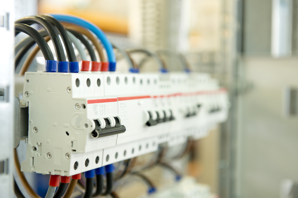 An electrical fuse box that is off with black, gray,  brown and blue wires. In need of a general electrician. 