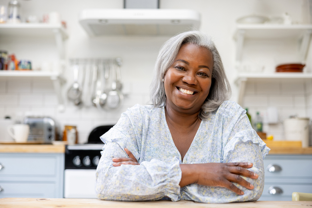 A smiling woman in her brightly lit home thanks to her general electrician. 