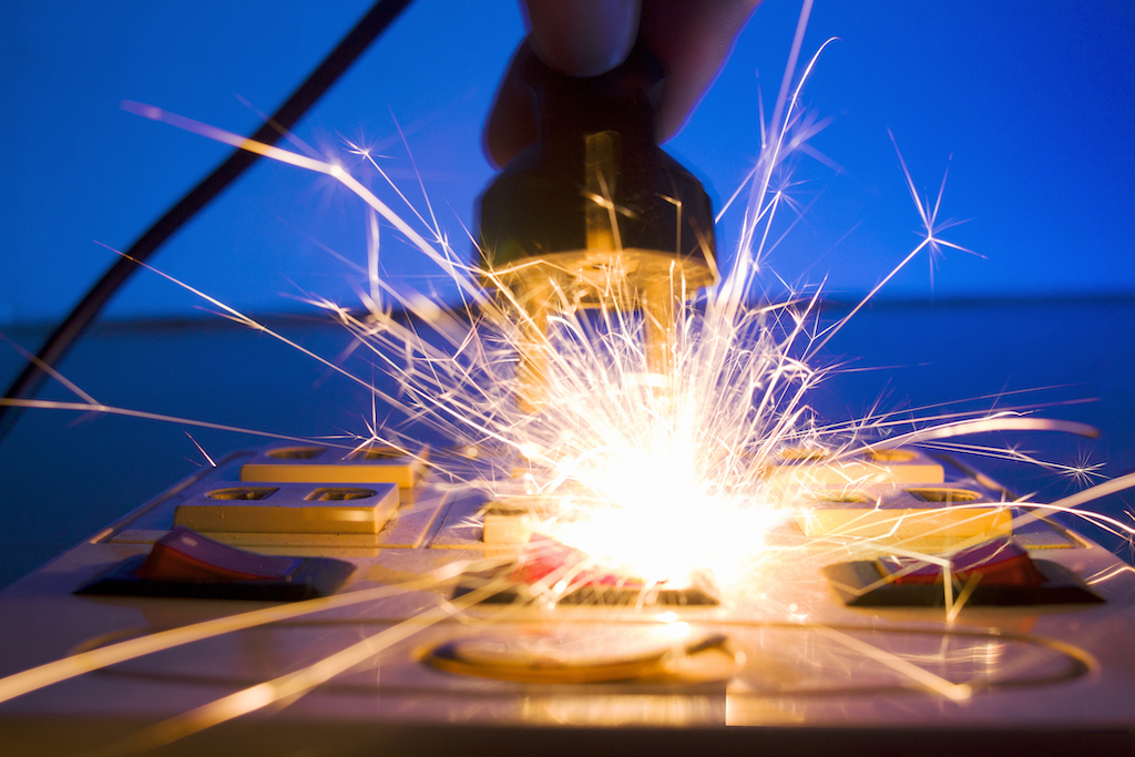 Person plugging into an outlet with a spark and shock, in need of electrical repair.