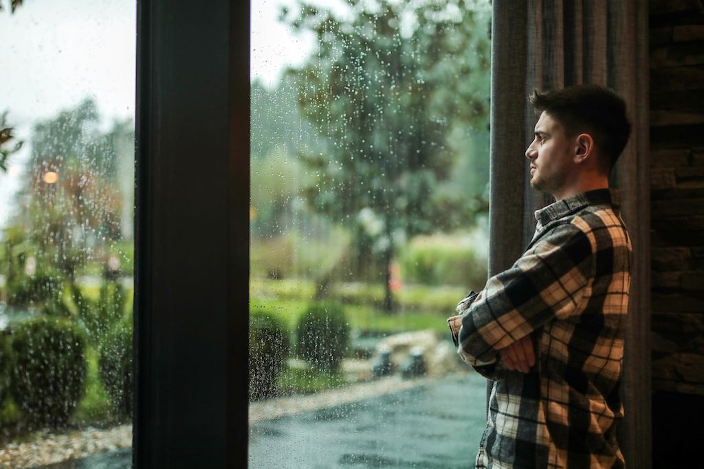 Man looking out window watching a storm. | Generator